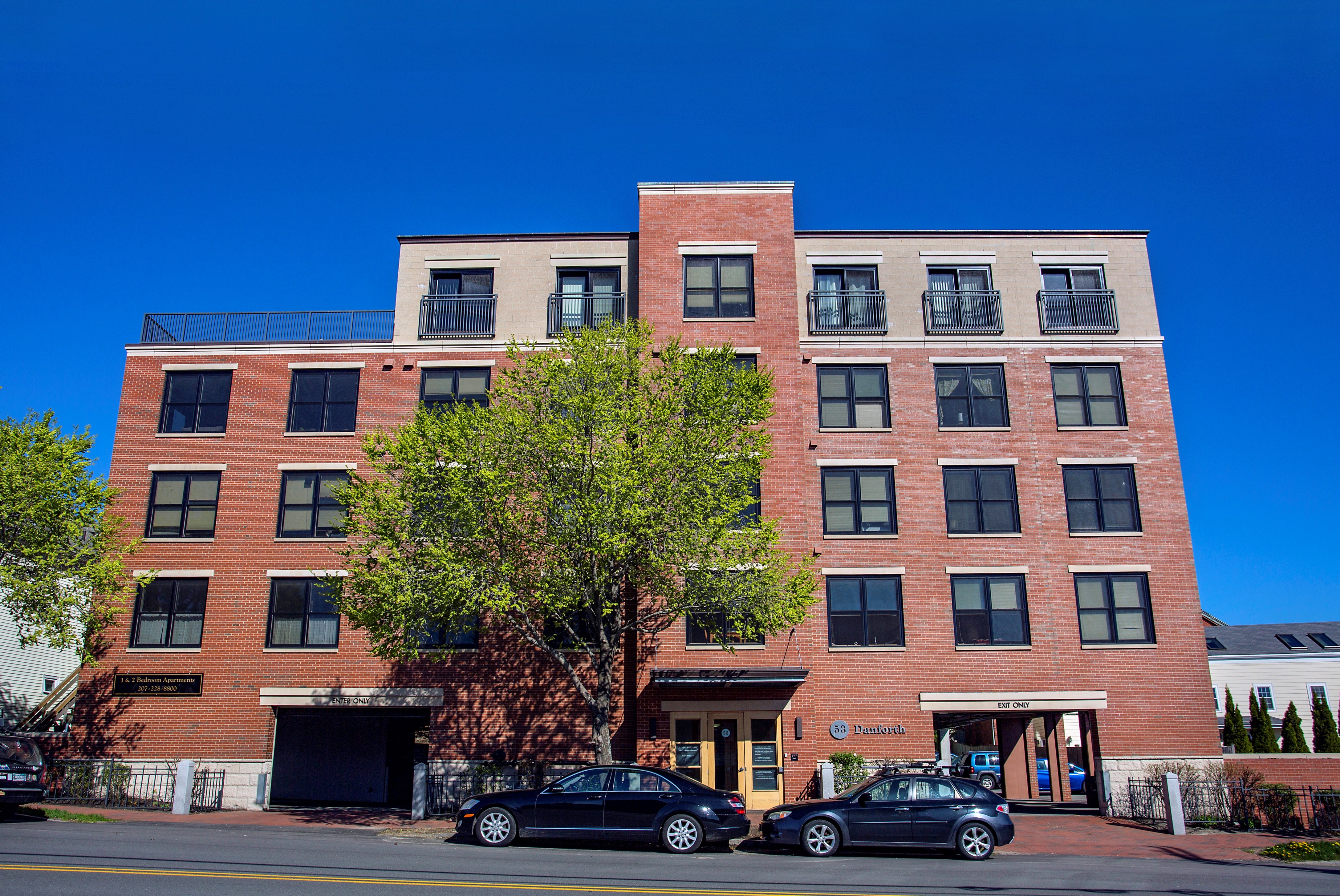 A red brick building with a tree in front of it.